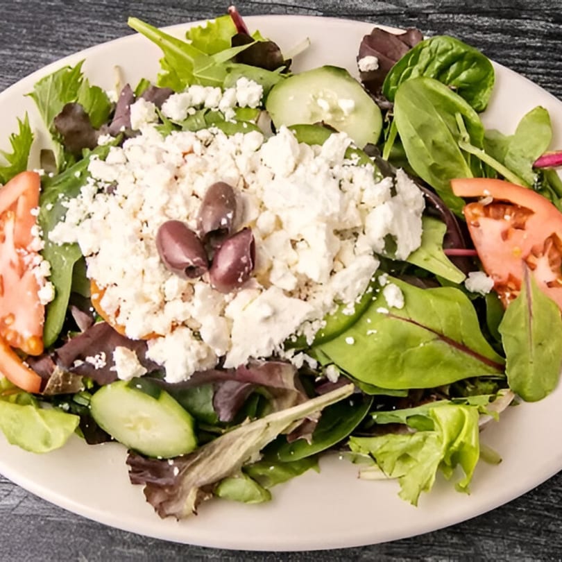 Fresh Bruno's Pizza house salad with mixed greens, tomatoes, cucumbers, feta cheese, and olives.