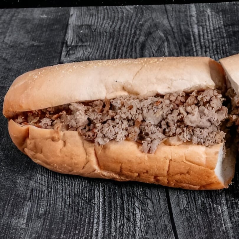 Bruno's Pizza cheesesteak sandwich, filled with chopped meat, on a dark wooden surface.